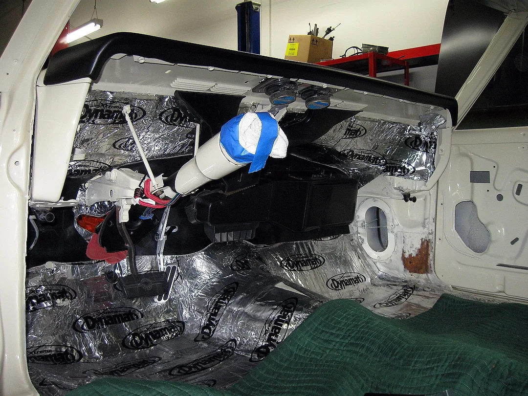 A car door with its trim off and sound-damping sheet applied to the panel