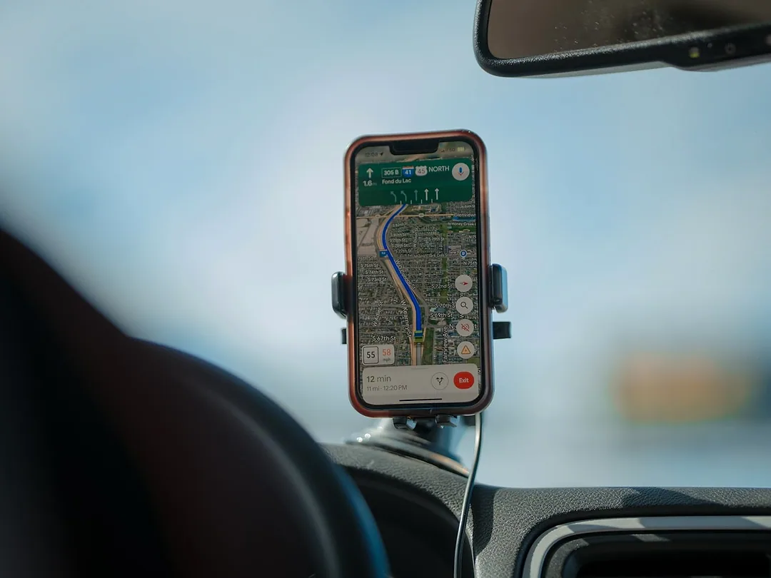 A phone showing navigation, held in a mount on a car's dashboard